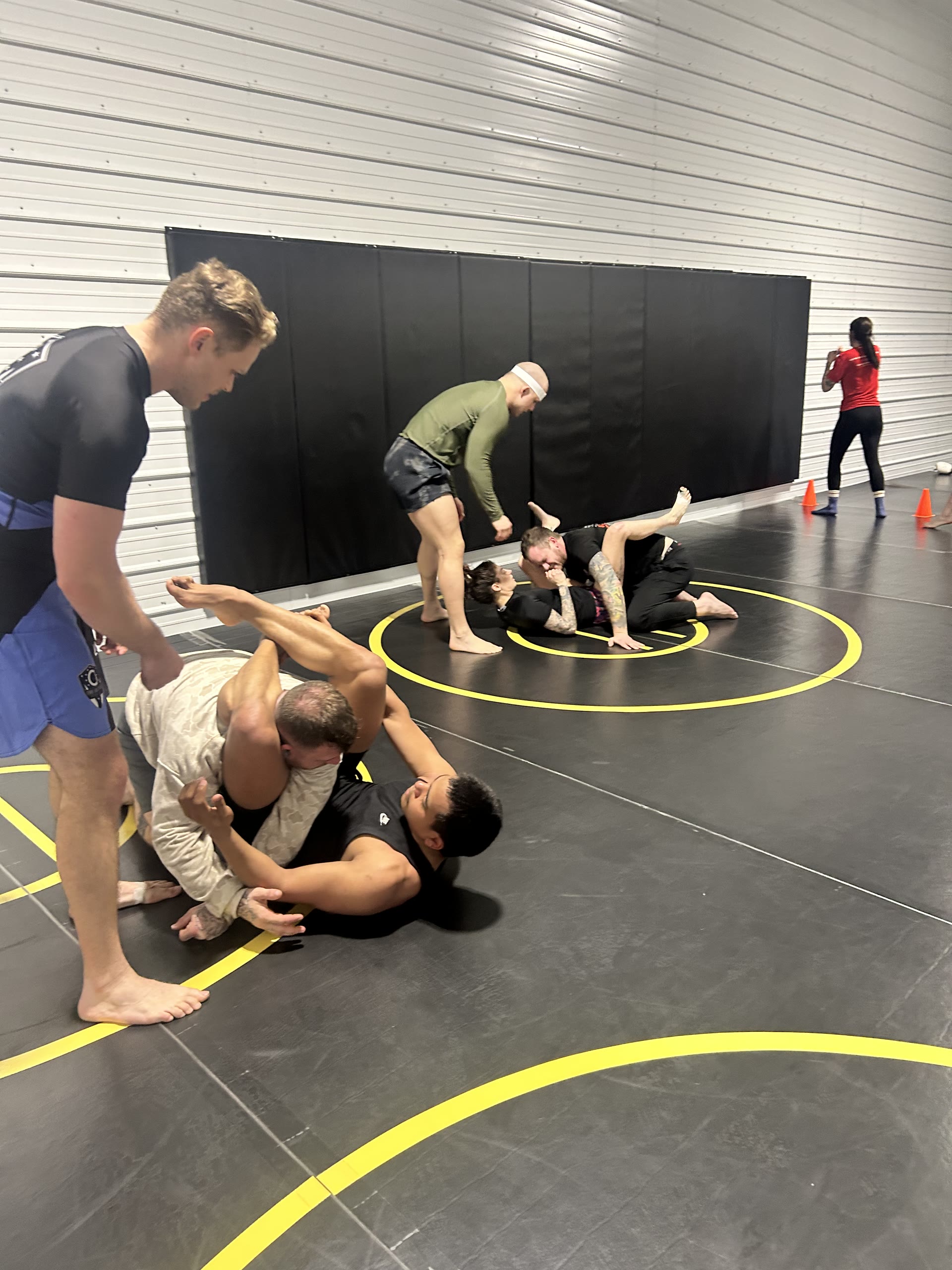 A full room of members drilling and rolling during open mat at Golden Oak Combat Club