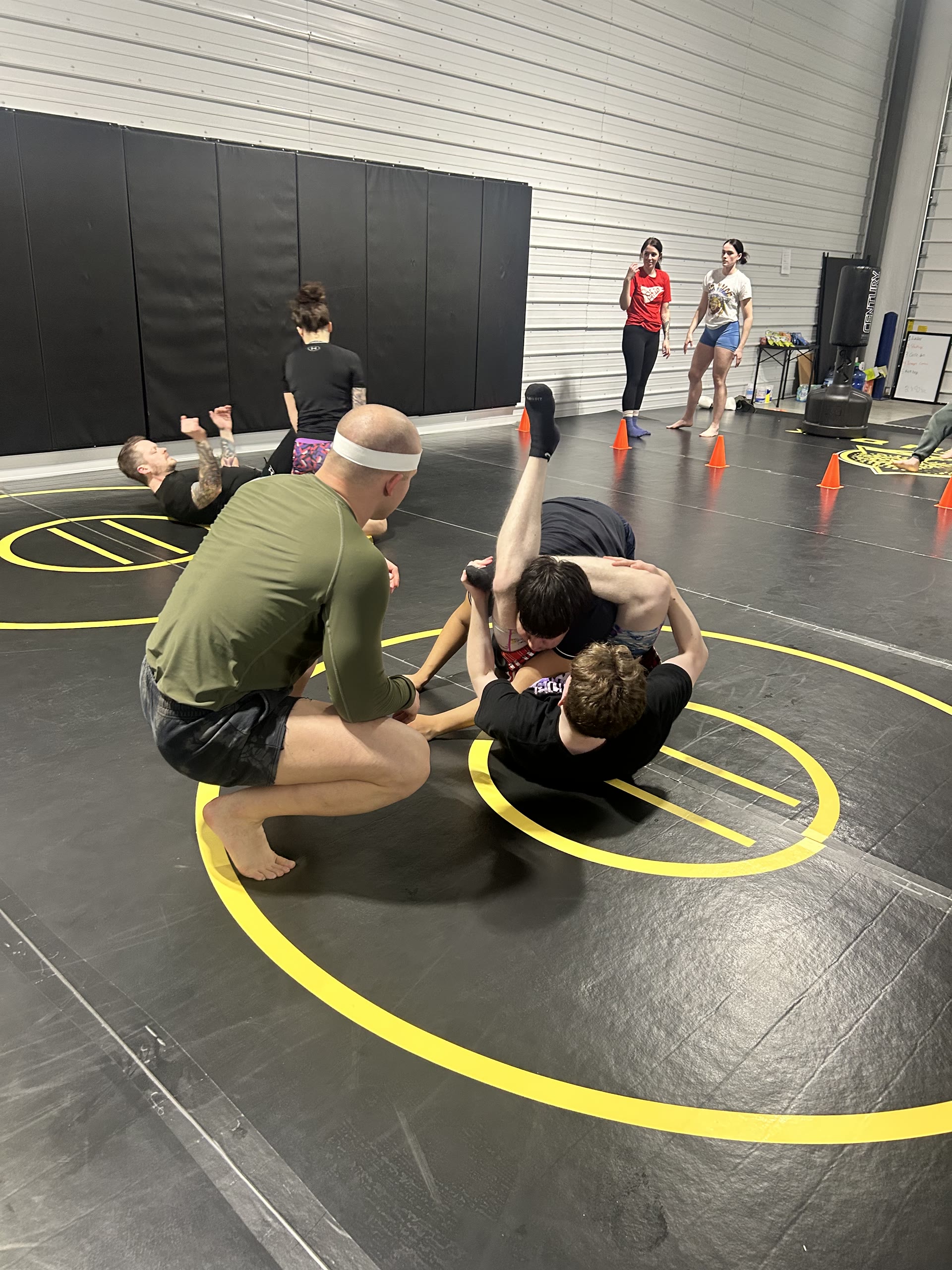 Coach demonstrating technique to a group of young athletes on the Golden Oak mats